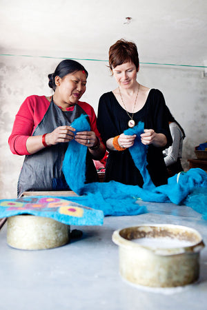 Jennifer Pulling and a woman smile while inspecting blue dyed felt